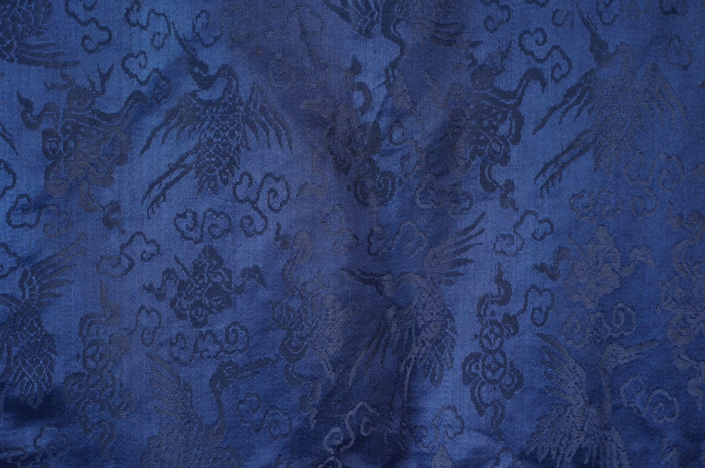 A late 19th century Chinese blue silk damask jacket, woven with Phoenix and auspicious symbols. The jacket edged with ornate rows of braiding and silk embroidery, the interior with original pink silk lining. The jacket f
